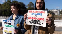 Protestors are holding card boards criticising Trump's Ukraine policy