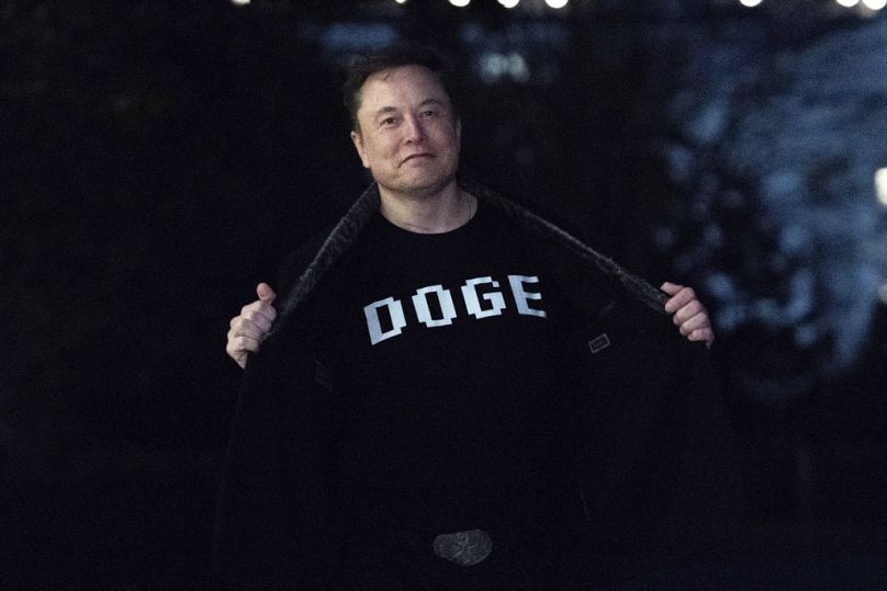 ألون ماسك يستعرض قميصه الذي يحمل كلمة "DOGE" أمام وسائل الإعلام أثناء سيره في الحديقة الجنوبية للبيت الأبيض في واشنطن، يوم الأحد 9 مارس 2025.