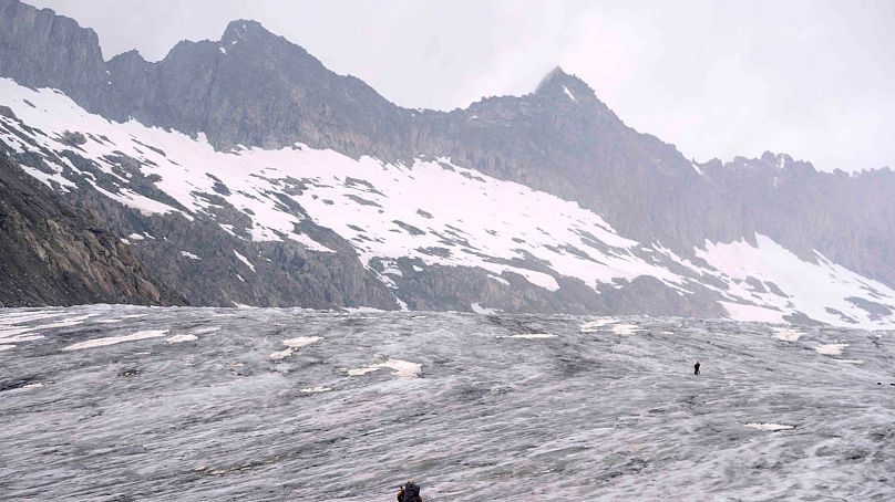 A cameraman walks up to the Rhone Glacier near Goms, Switzerland, June 2023.