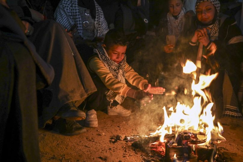 صبي يتدفأ بينما تنتظر عائلات وأصدقاء الأسرى الفلسطينيين المقرر الإفراج عنهم من السجون الإسرائيلية حول موقد نار في خان يونس، جنوب قطاع غزة.