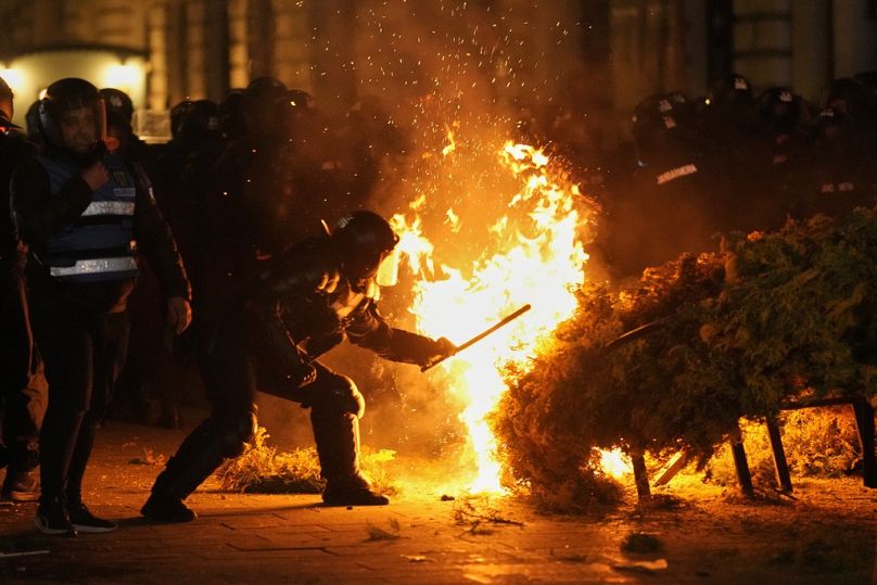 Policja próbuje ugasić pożar, gdy zwolennicy Calina Georgescu protestują po tym, jak rumuński organ wyborczy odrzucił jego kandydaturę w wyborach prezydenckich.