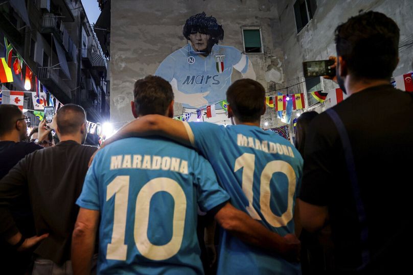 People gather in front of a giant mural of Diego Armando Maradona as they pay their homage and commemorate the late football legend on his birthday, in Naples, 30 October 2022
