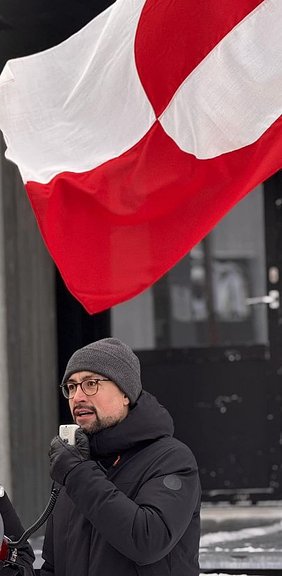 Múte Bourup Egede grönlandi kormányfő a grönlandi zászló alatt