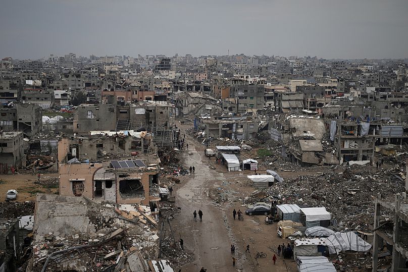 فلسطينيون يسيرون وسط ركام المنازل والمباني المدمرة في حي الزيتون في مدينة غزة، الجمعة 7 مارس/آذار 2025