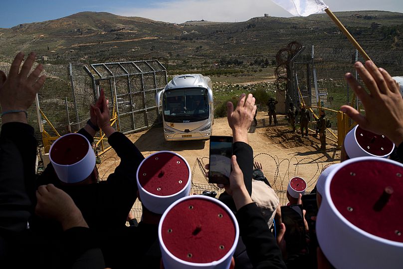 رجال دين دروز يستقبلون حافلات تقل أبناء الطائفة الدرزية السورية على الحدود مع سوريا، أثناء دخولهم إلى قرية مجدل شمس ، الجمعة، 14 مارس/آذار 2025