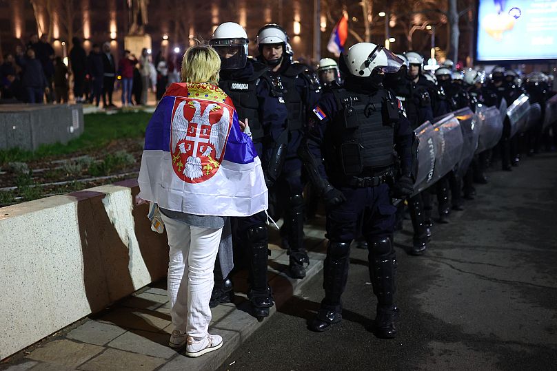 Une manifestante face à des policiers lors d'un grand rassemblement contre le président Aleksandar Vučić et son gouvernement, à Belgrade, Serbie, samedi 15 mars 2025.