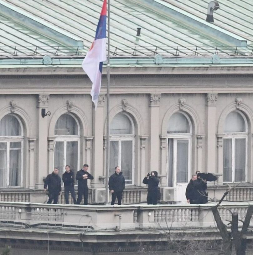 Feketeruhás férfiak az elnöki hivatal erkélyén Belgrádban, 2025. március 15-én