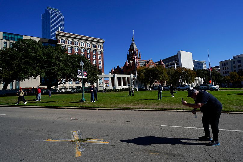 Homem tirando fotos do local onde John F. Kennedy foi morto, em Dallas, em 1963