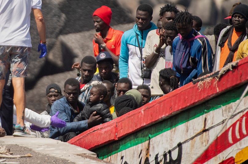 A child is carried ahore from a crowded wooden boat in the port in La Restinga on the Canary Island of El Hierro, 18 August, 2024