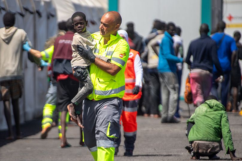 A child is carried by an emergency team member after being rescued from a boat in the port in La Restinga on the Canary Island of El Hierro, 18 August, 2024