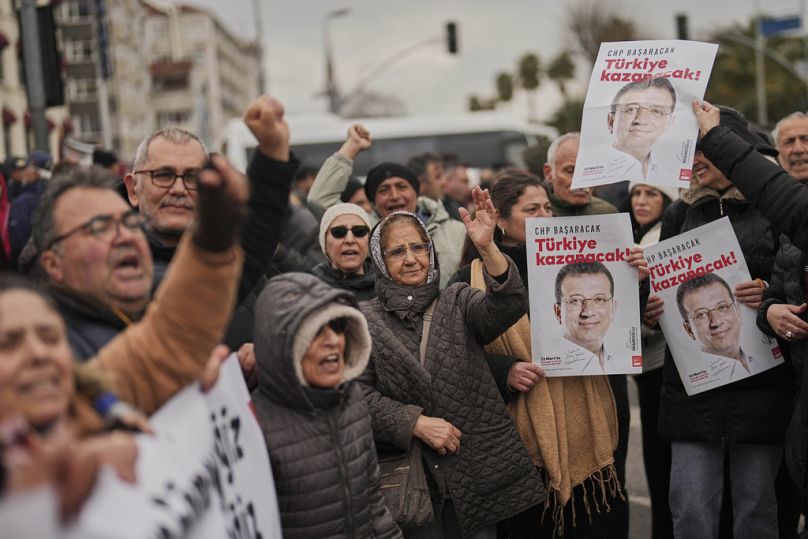 Menschen halten Plakate des Istanbuler Bürgermeisters Ekrem Imamoglu, während sie vor dem Vatan-Sicherheitsamt in Istanbul, Türkei, protestieren, Mittwoch, 19. März 2025.