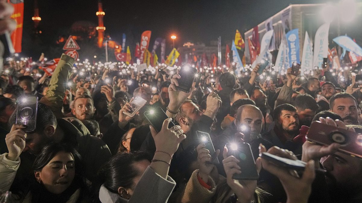 People raise their mobile phones as they gather outside the City Hall to protest the arrest of Istanbul Mayor Ekrem Imamoglu in Istanbul, Turkey, on 19 March, 2025.