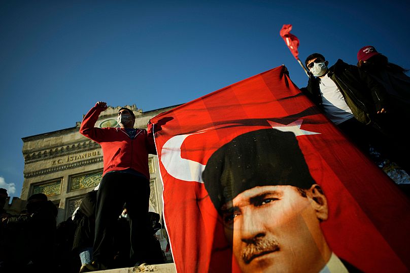 University students hold a Turkish flag with the image of Turkey's founding father Mustafa Kemal Ataturk in Istanbul, 21 March, 2025