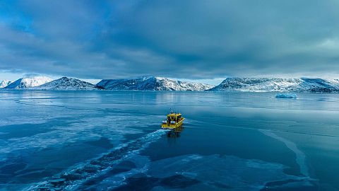 A boat travels though a frozen sea inlet outside in Nuuk, Greenland.