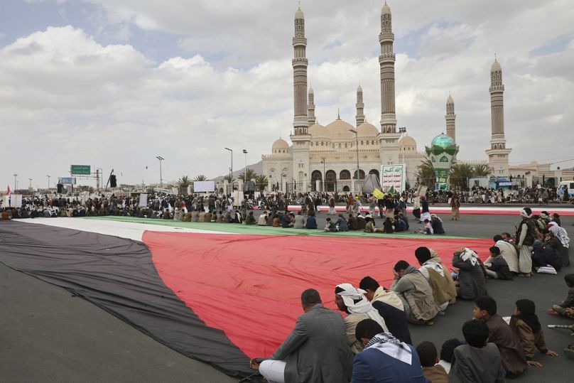 أنصار جماعة الحوثيين يرفعون علمًا فلسطينيًا ضخمًا خلال تظاهرة أسبوعية مناهضة للولايات المتحدة وإسرائيل في صنعاء، اليمن، يوم الجمعة 28 آذار/مارس 2025.
