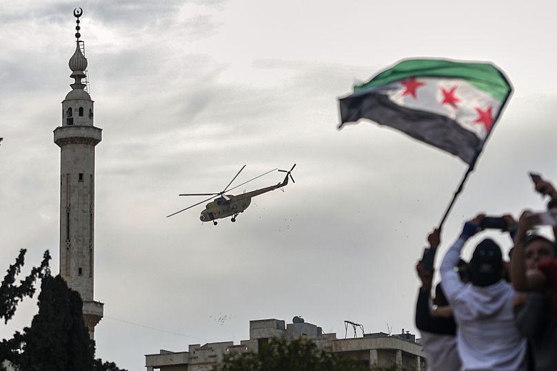 قصاصات الورود والورود تتساقط من مروحية عسكرية على حشد من الناس في إدلب، سوريا، الجمعة، 28 مارس/آذار 2025