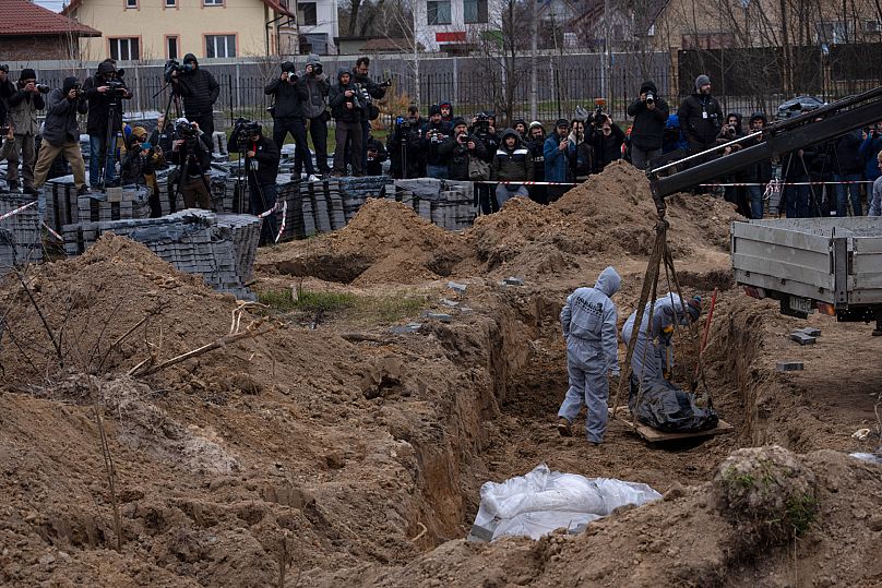Un employé de cimetière exhume le corps d'un civil tué à Boutcha d'une fosse commune, dans la banlieue de Kyiv, en Ukraine, le mercredi 13 avril 2022.