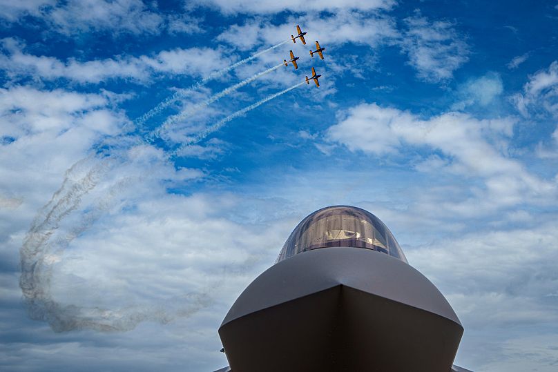 A Romanian air acrobatics team performs above a US Air Force F35 Lightning II fighter jet in Bucharest, 22 May, 2024