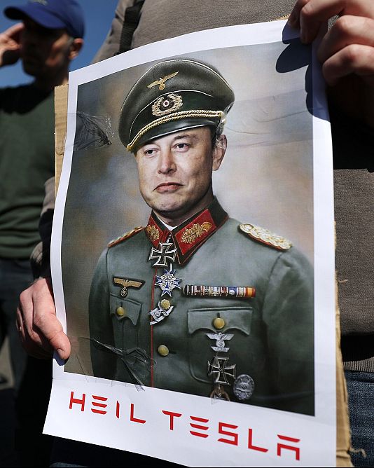 Elon Musk náci egyenruhában egy tiltakozó kezében tartott képen, Londonban, 2025. március 29-én
