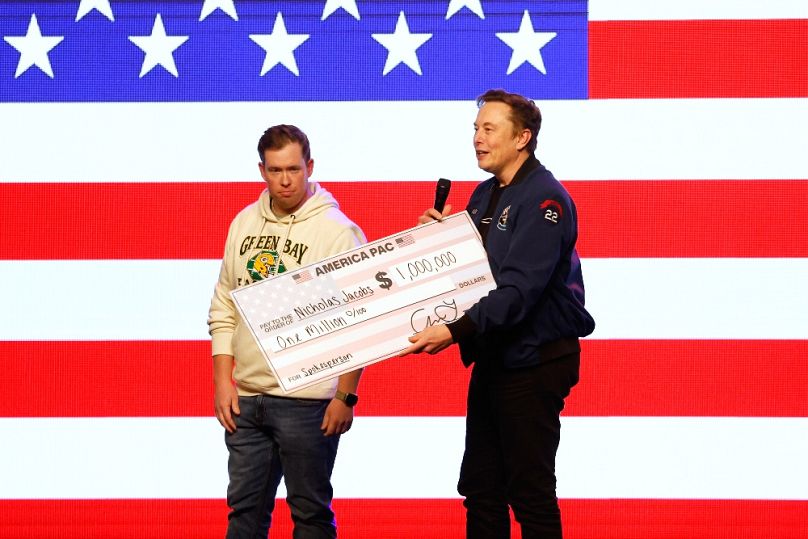 Elon Musk egymillió dolláros csekket ad át egy szavazónak a wisconsini Green Bay-ben, 2025. március 30-án