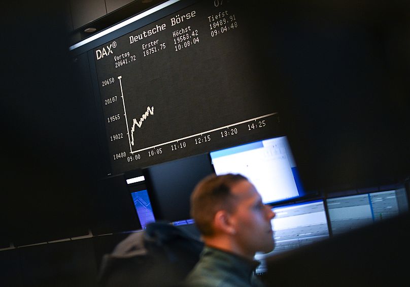 Trader giełdowy siedzi przed swoimi monitorami na parkiecie giełdy we Frankfurcie, Niemcy