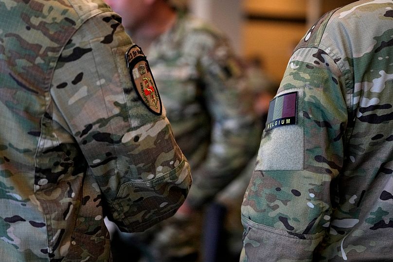 Soldados da Bélgica e do Luxemburgo alinham-se enquanto se preparam para embarcar num avião de transporte militar no Aeroporto Militar de Melsbroek, 4 de julho de 2023