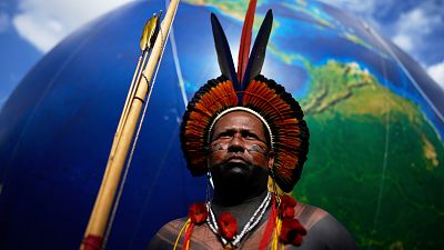 An Indigenous man stands next to a large earth balloon during the march coined: "We are the answer" in Brasilia, Brazil, Thursday, April 10, 2025