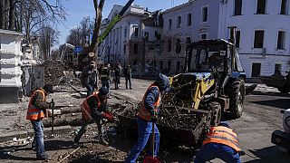 Муниципальные рабочие убирают улицу перед зданием университета, повреждённым в результате российского ракетного удара по Сумах, 14 апреля 2024 года.