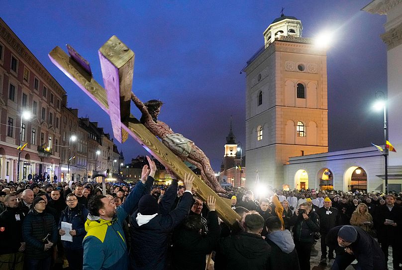 Wierni trzymają krzyż podczas procesji Drogi Krzyżowej w centrum Warszawy, Polska, piątek, 15 kwietnia 2022 r.