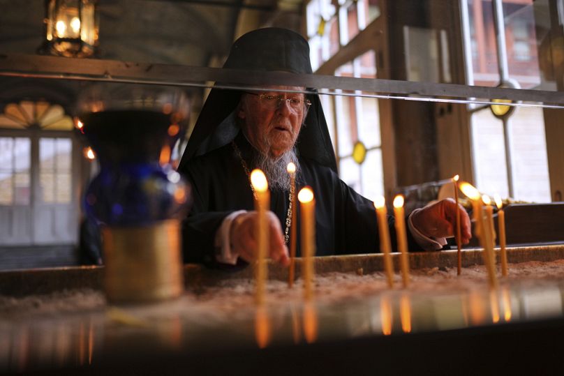 Patriarcha Bartłomiej I, duchowy przywódca prawosławnych chrześcijan, zapala świece, gdy przybywa, aby poprowadzić nabożeństwo Męki Pańskiej, 17 kwietnia 2025 r.