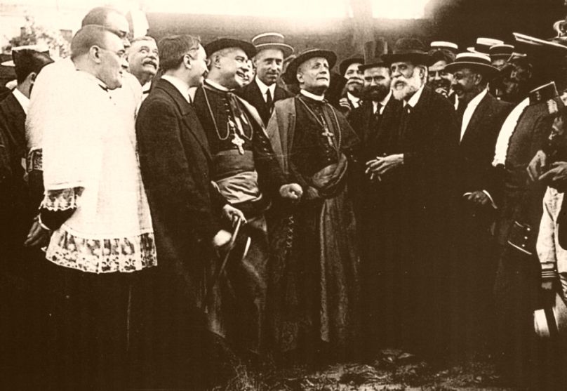 Monsignor Remigio Ragonesi 1915-ben megtekintette a Sagrada Família munkaterületét, a balján Antoni Gaudí