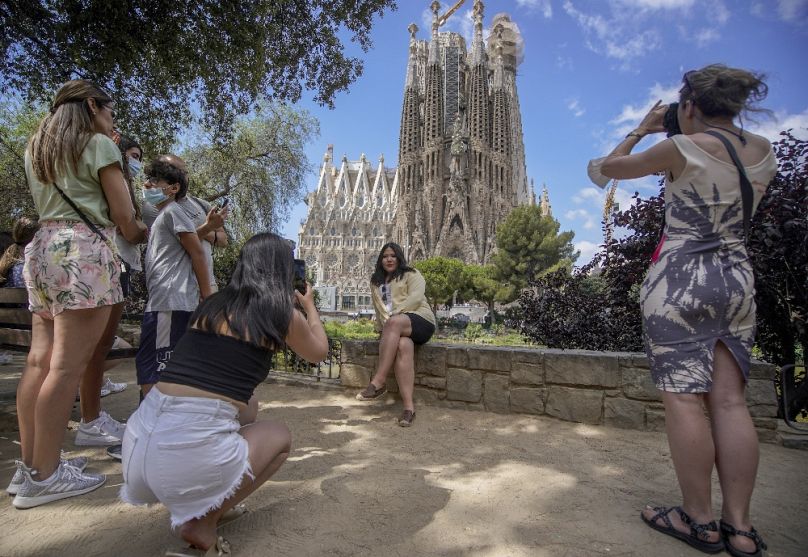 Turisták Barcelonában, a háttérben a Sagrada Família, 2021 júliusában