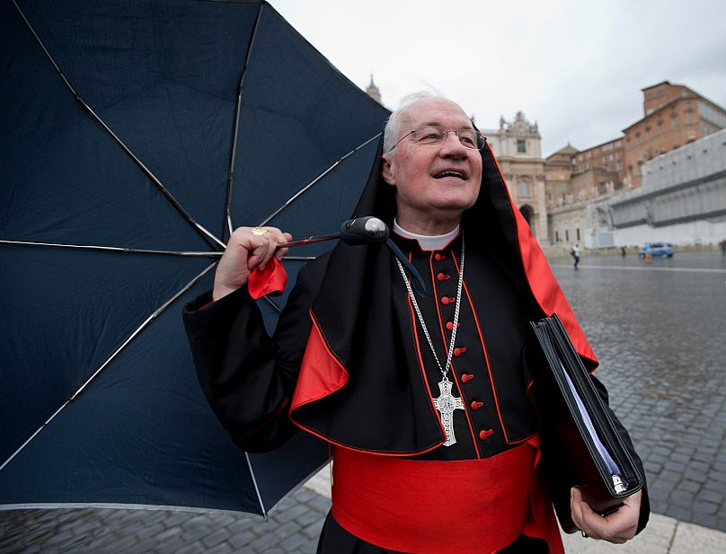 El cardenal canadiense Marc Ouellet se aferra a su paraguas en un día ventoso mientras camina por la Plaza de San Pedro en el Vaticano, el 6 de marzo de 2013.