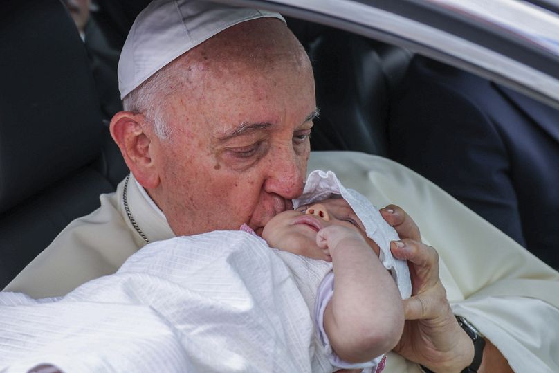 O Papa Francisco dá um beijo a uma criança a caminho do Centro Cultural de Belém, em Lisboa, a 2 de agosto de 2023. 