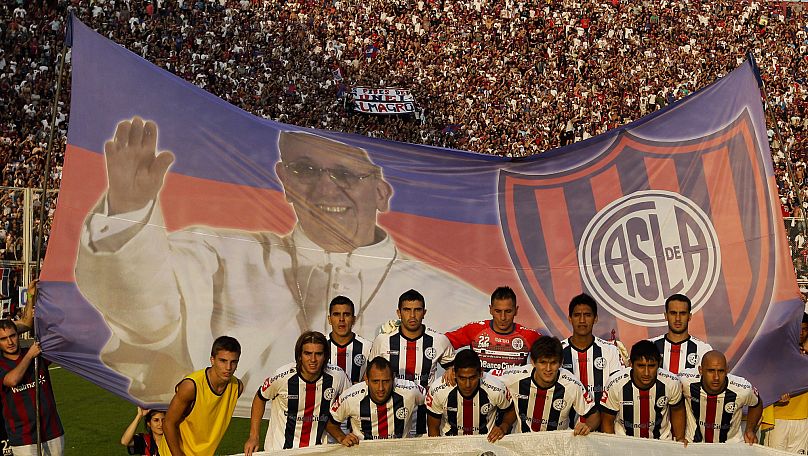 El equipo de San Lorenzo de Almagro posa frente a una pancarta con la foto del Papa Francisco y los colores del equipo antes de un partido de la liga argentina de fútbol.