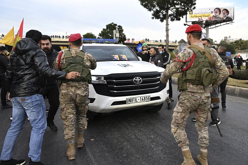 جنود من الجيش اللبناني يوفّرون الحماية لقافلة لقوات اليونيفيل، بينما يحاول مناصرو حزب الله قطع الطريق المؤدي إلى مطار بيروت الدولي يوم السبت 15 فبراير 2025. 