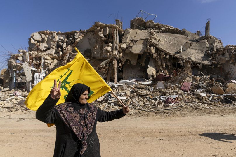 امرأة لبنانية ترفع علم حزب الله في قريتها المدمرة جراء الهجوم الإسرائيلي، في بلدة كفركلا جنوب لبنان، يوم الثلاثاء 18 فبراير 2025.