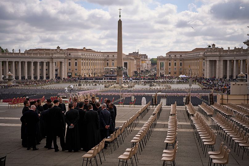 Des prêtres et du personnel de sécurité se rassemblent devant la basilique Saint-Pierre, au Vatican, le vendredi 25 avril 2025