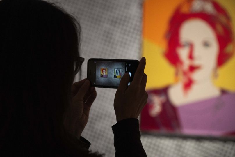 Une femme prend une photo d'œuvres d'art représentant la reine Beatrix des Pays-Bas,  à Apeldoorn, Pays-Bas, mercredi 9 octobre 2024.