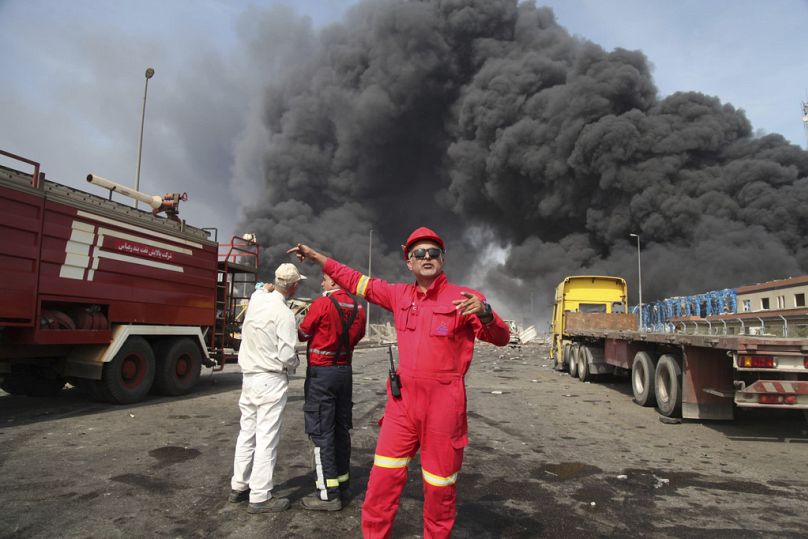 Sur cette photo fournie par l'Agence de presse de la République islamique (IRNA), des pompiers travaillent alors qu'une fumée noire s'élève dans le ciel après une explosion 