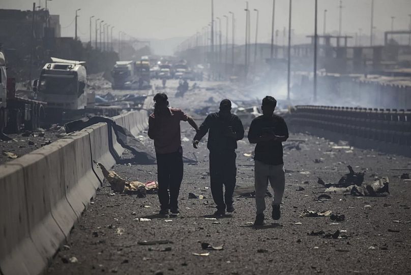 İran Haber Ajansı IRNA'nın sağladığı bu fotoğrafta, patlamadan sonra enkazın arasında yürüyen kişiler görülüyor, 26 Nisan 2025.