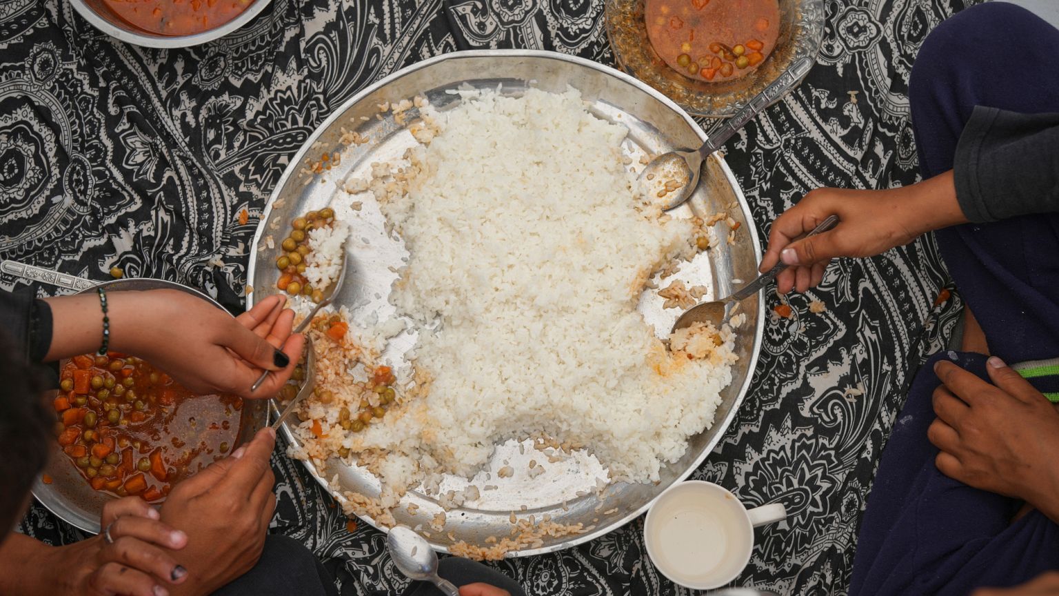 The Al-Najjar family eats peas with rice in their family tent in Muwasi, on the outskirts of Khan Younis in the southern Gaza Strip, Friday, April, 25, 2025.