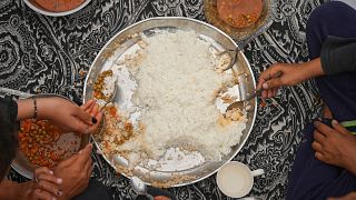 The Al-Najjar family eats peas with rice in their family tent in Muwasi, on the outskirts of Khan Younis in the southern Gaza Strip, Friday, April, 25, 2025.