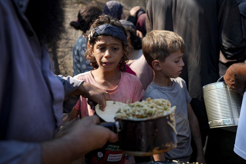 فلسطينيون يصطفون لتلقي المساعدات الغذائية في دير البلح، قطاع غزة – 17 تشرين الأول/ أكتوبر 2024.