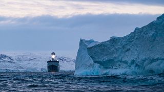 The Royal Danish Navy frigate HDMS Triton passing an iceberg in the waters around Greenland