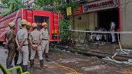 Feuerwehrleute stehen bereit, während Polizisten den Eingang eines Hotelgebäudes bewachen, das am Dienstag in Brand geriet und mehrere Todesopfer forderte, in Kolkata, Indien, Mittwoch, 30. April 2025