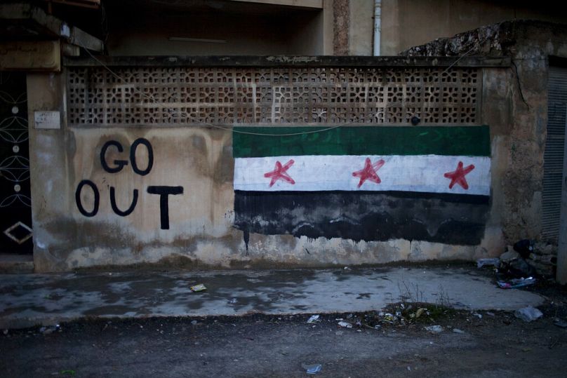 رسم جداري يظهر علم "الثورة السورية" وشعار "ارحل" على أطراف إدلب شمال سوريا، 1 آذار/مارس 201     