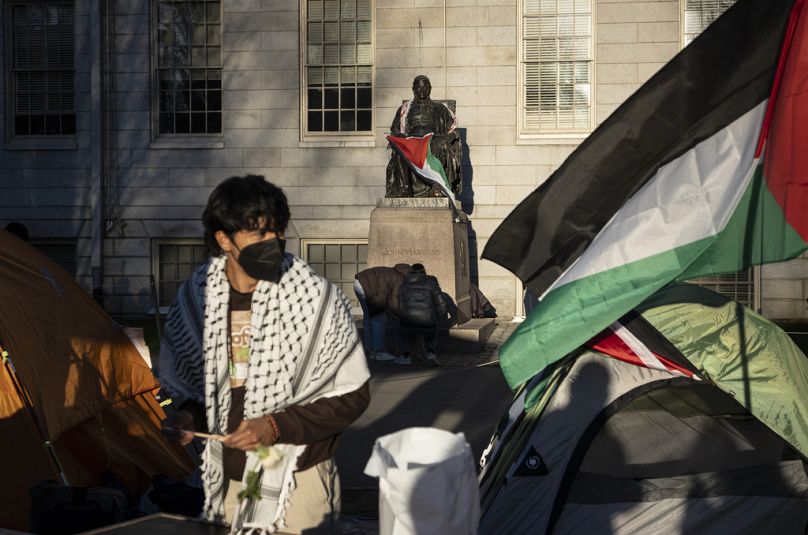 Uno studente protesta davanti alla statua di John Harvard con la bandiera palestinese, Cambridge, Massachusetts, 25 aprile 2024