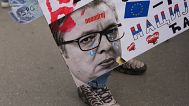 A woman holds a poster that shows Serbian President Aleksandar Vucic in Novi Sad, Serbia, Friday, April 25, 2025.