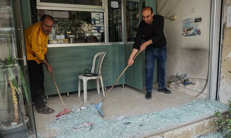 عدد من الأشخاص يقومون بإزالة الزجاج المحطم من متجر تضرر بعد اندلاع اشتباكات بين أفراد من الطائفة الدرزية الأقلية ومقاتلين موالين للحكومة، في بلدة صحنايا، الخميس 1 مايو 2025